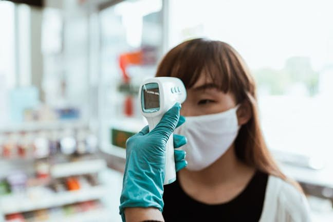 woman in mask getting temperature taken