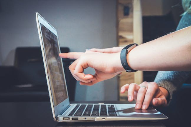 two people pointing at a laptop screen