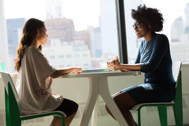 two women sitting at a table talking