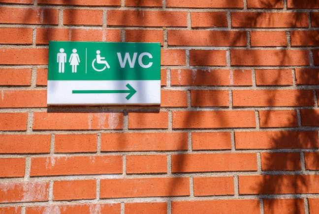 red brick wall with green wc sign