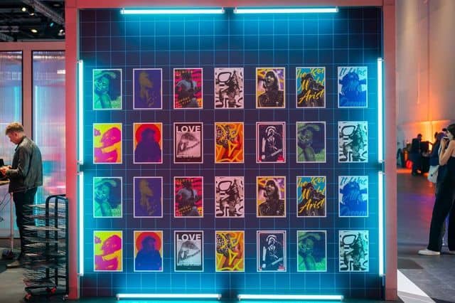 A grid of unique AI-generated album covers displayed on a neon-lit wall at Xerocon, created by INVNT
