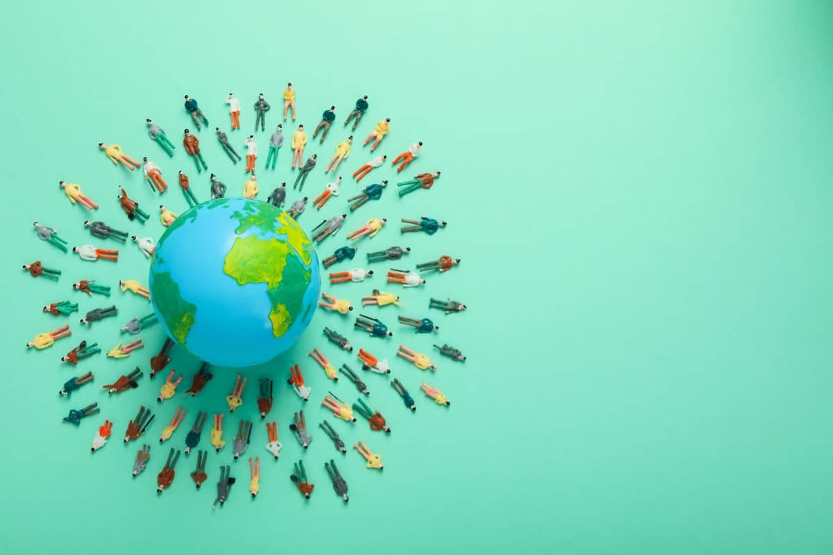 People figures surrounding earth on green background
