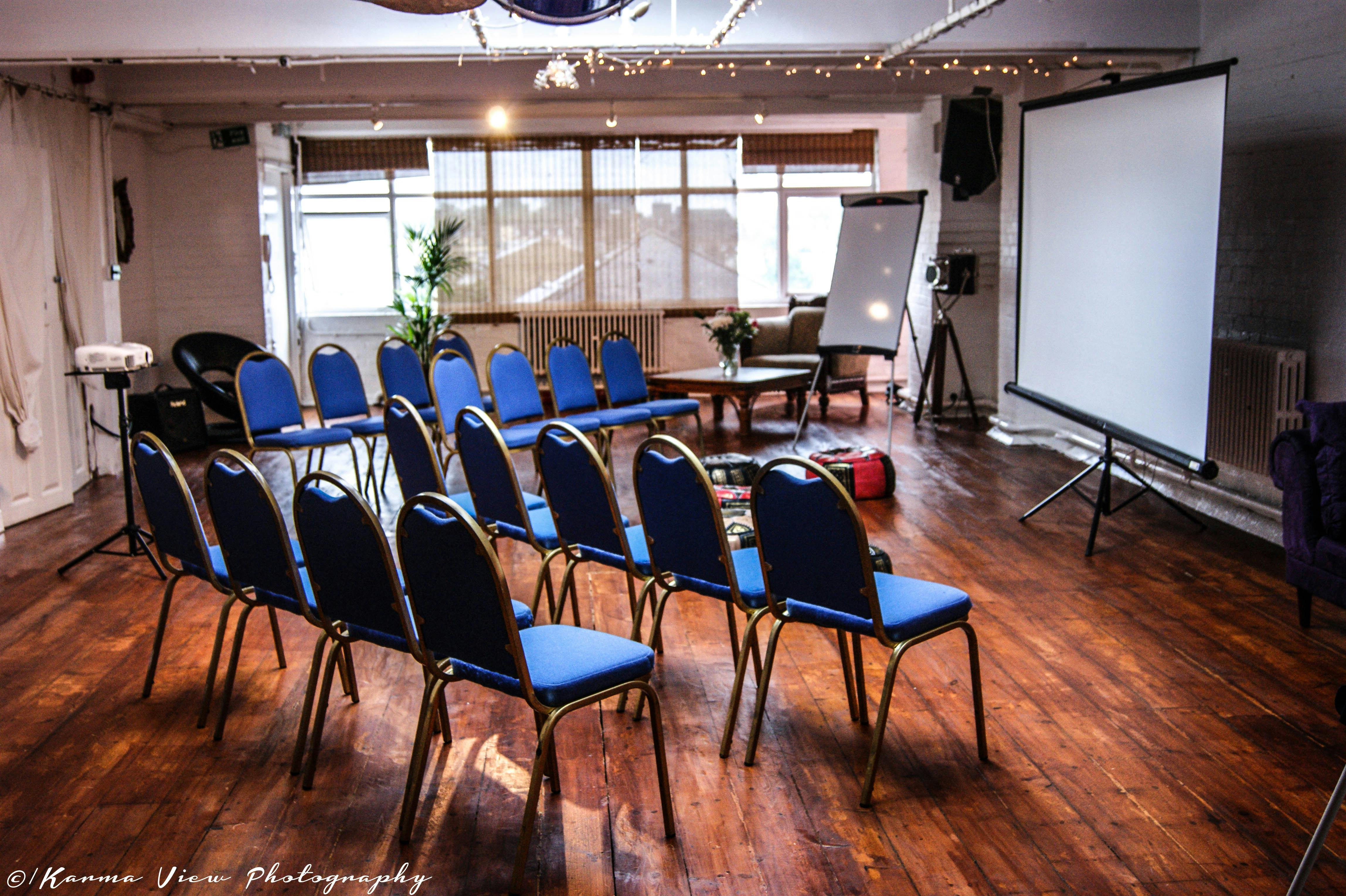 Meeting space with blue chairs and projection screen, perfect for workshops and presentations.