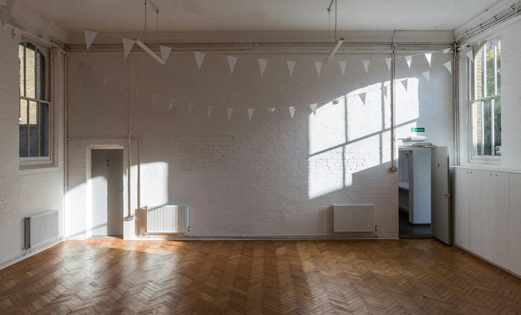 Bright minimalist event space in Saint Barnabas Dalston with natural light and bunting.