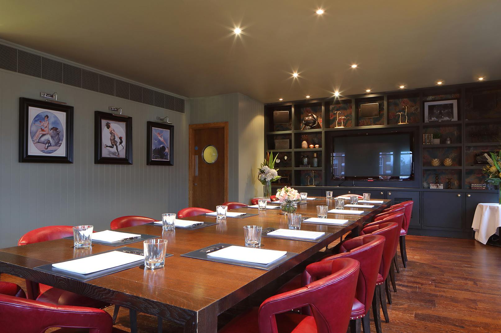 Private dining room with wooden table and red chairs, ideal for meetings and events.