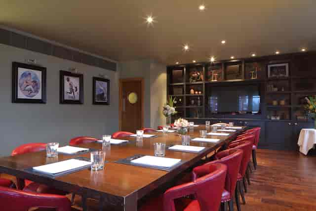 Private dining room with wooden table and red chairs, ideal for meetings and events.