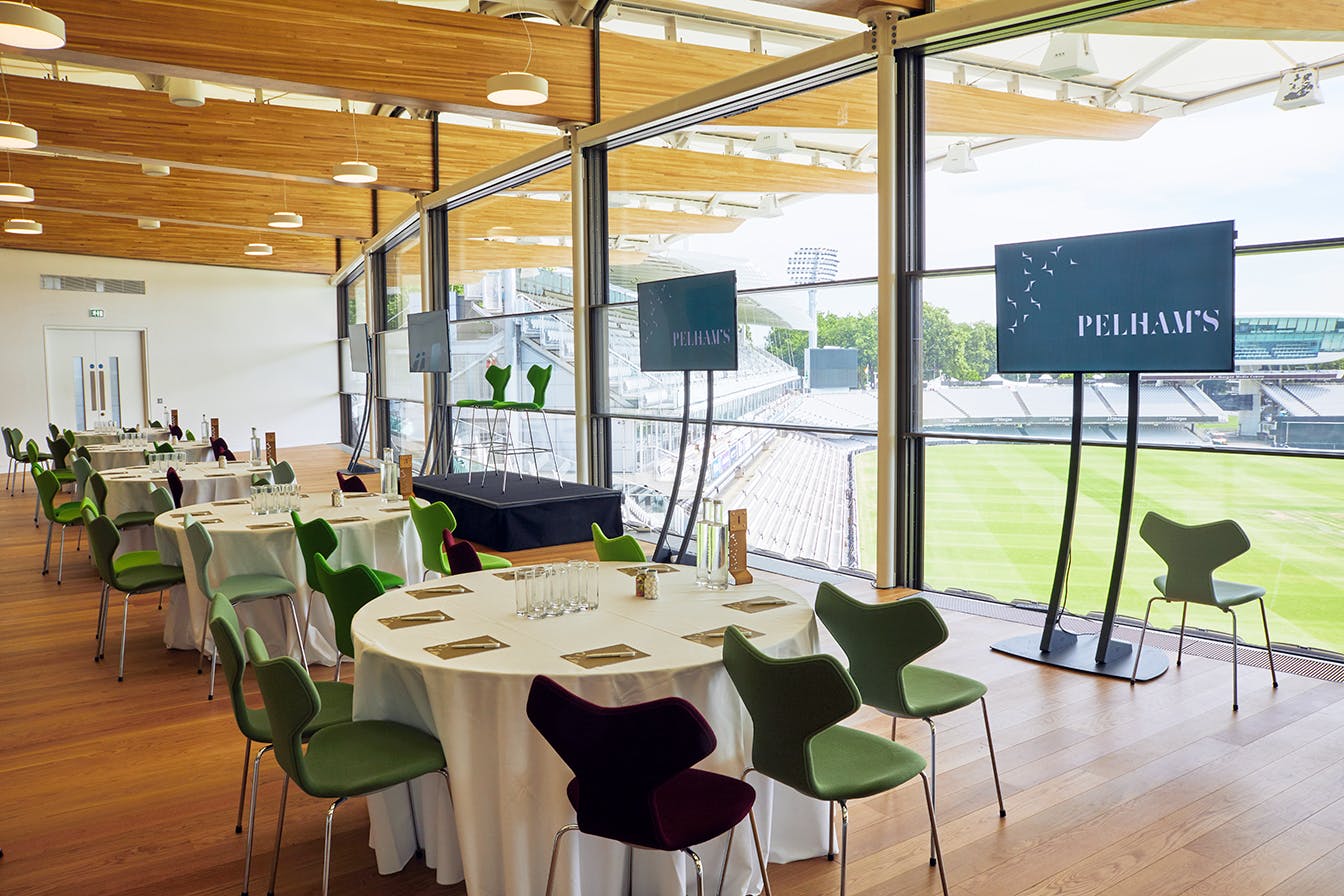Modern event space at Lord's Cricket Ground with round tables for corporate meetings.