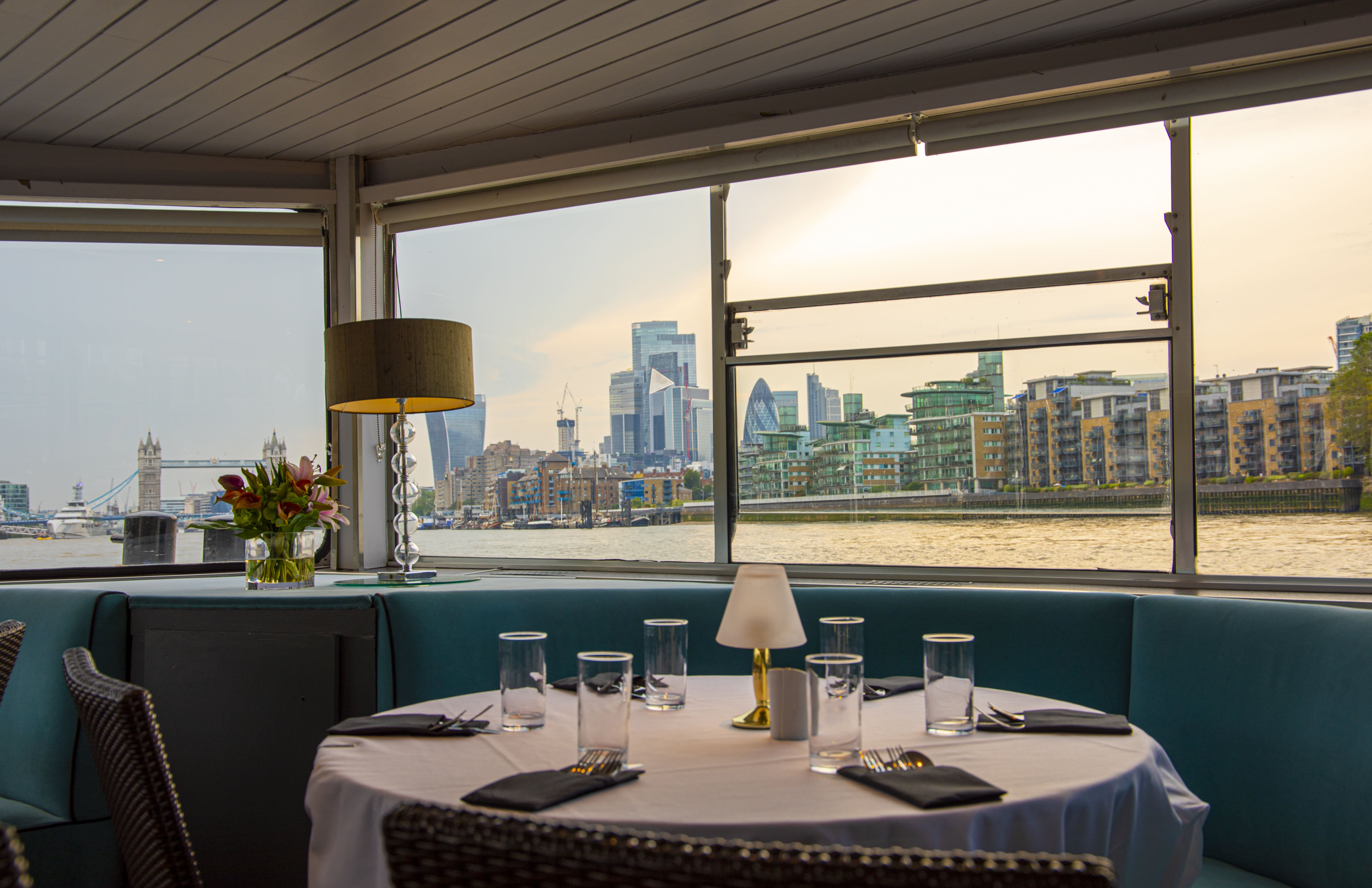 Elegant dining setup on M.V. Erasmus with London skyline, ideal for upscale events. - Banner