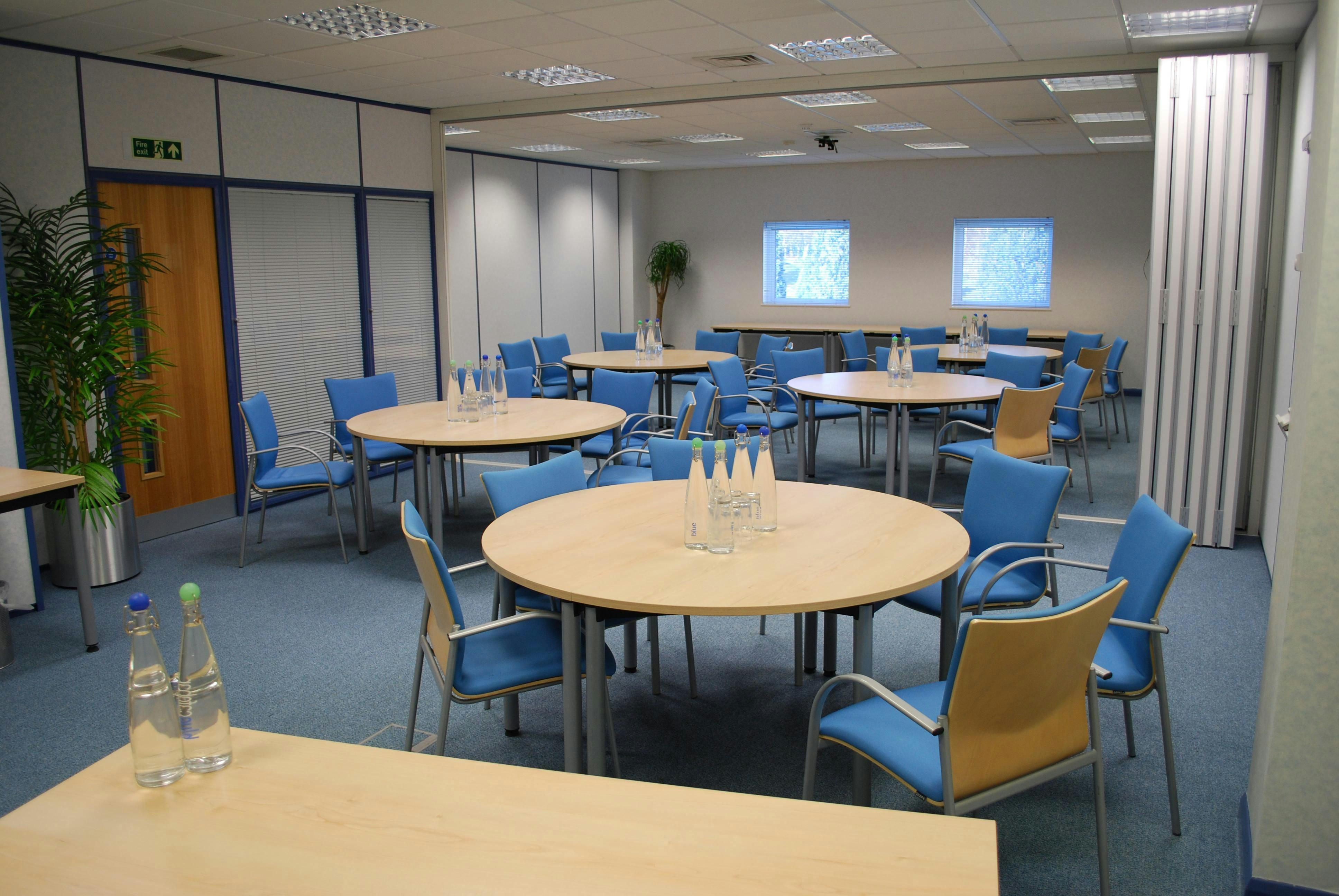 Meeting room at The Ark Conference Centre with circular tables and modern blue chairs.