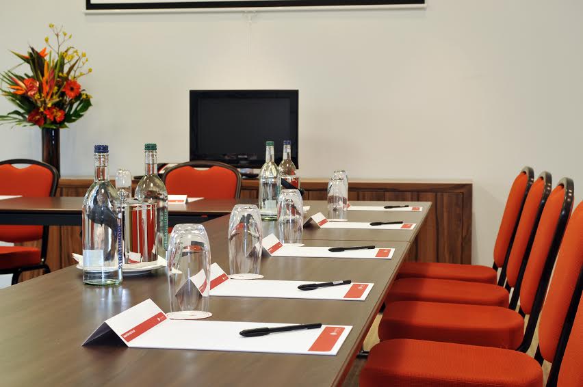 Supernova Suite meeting room with polished table, vibrant chairs for corporate events.
