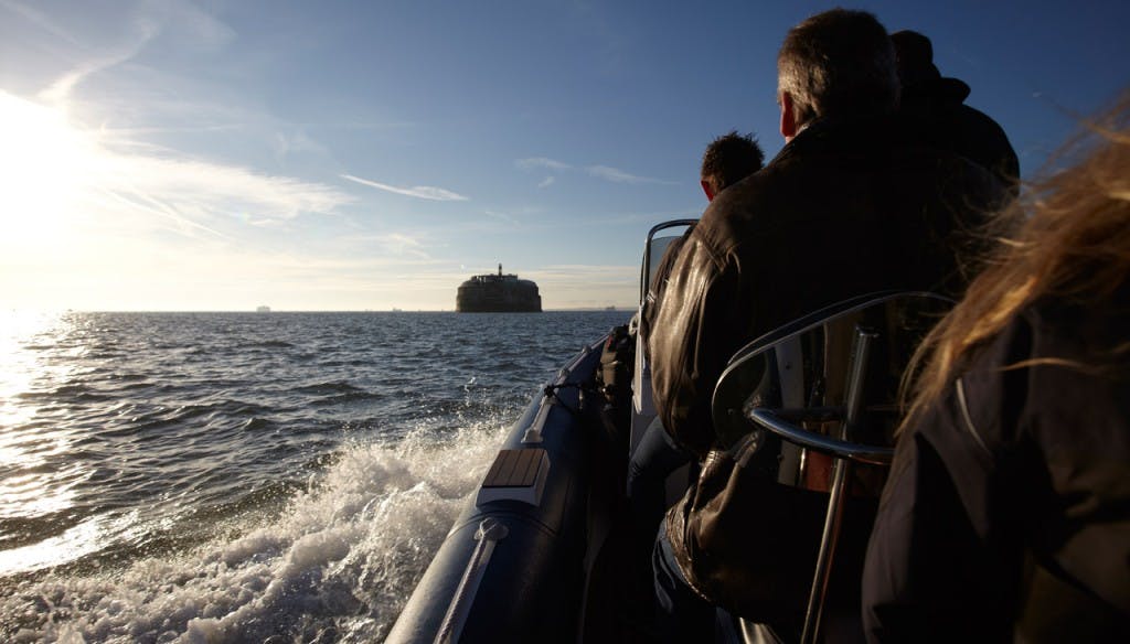 Group on boat approaching No Man's Fort for unique team-building events.