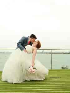 Romantic wedding couple in No Man's Fort with elegant water backdrop.