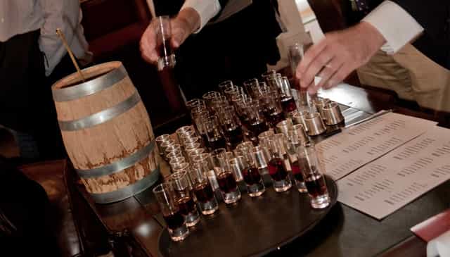 Boardroom tasting station with wooden barrel and shot glasses for networking events.