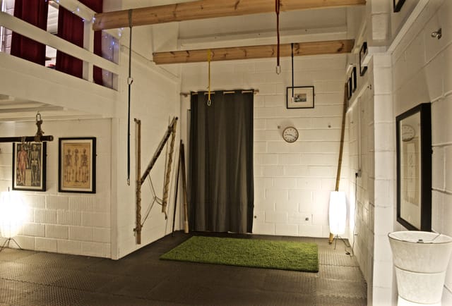 Versatile minimalist event space with wooden beams for intimate gatherings and workshops.