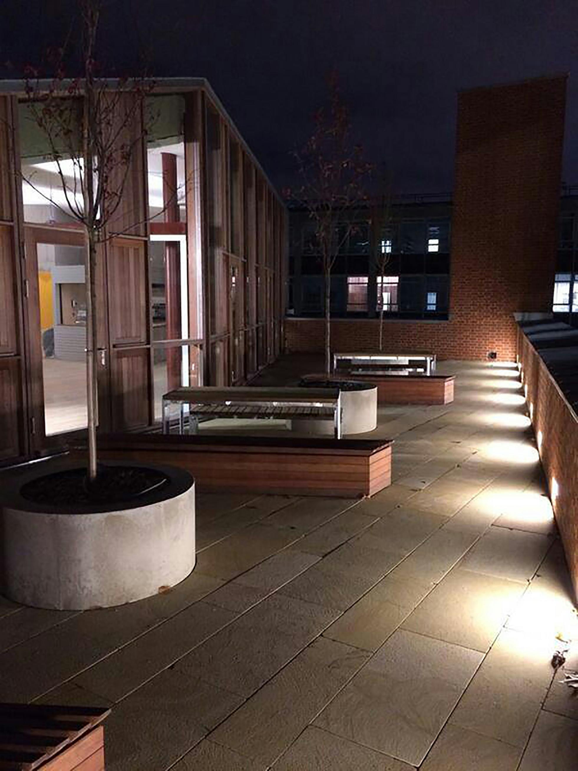 Outdoor networking space at The Weston Bar with ambient lighting and greenery.