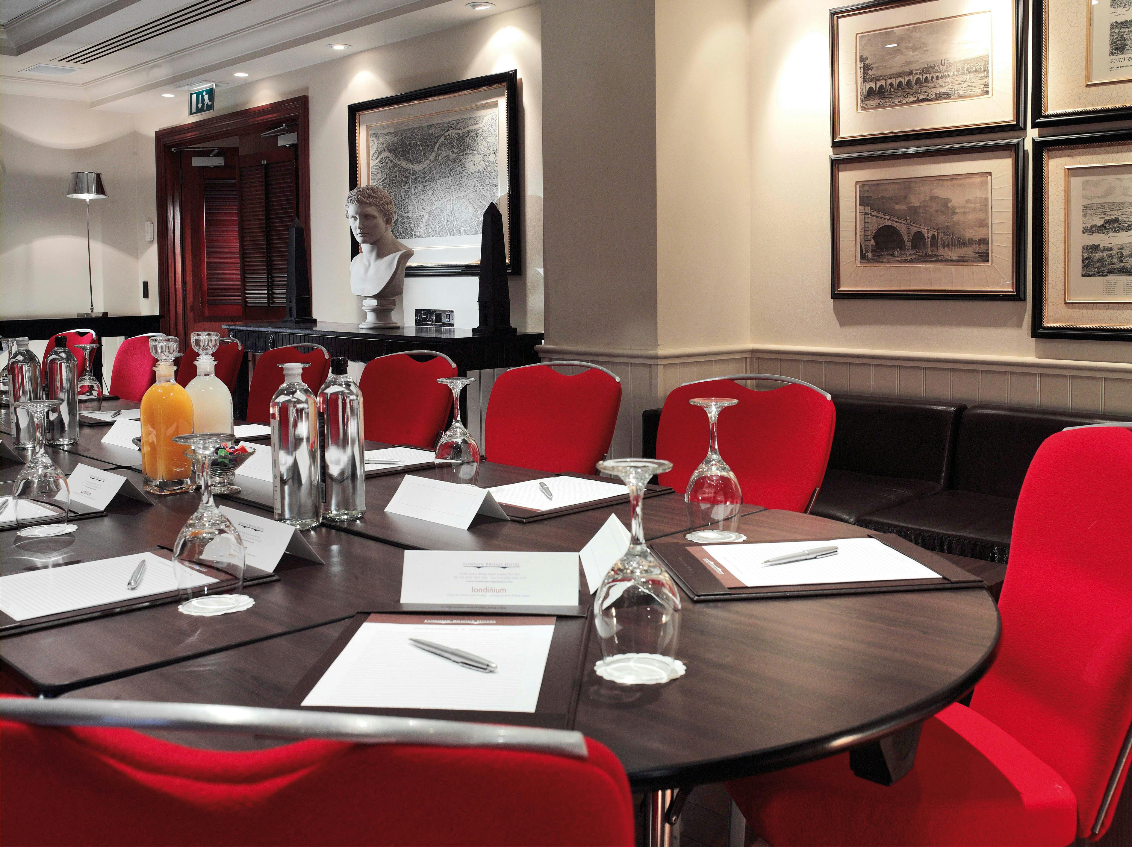 Bridge Suite meeting room in London Bridge Hotel with round table and vibrant red chairs.