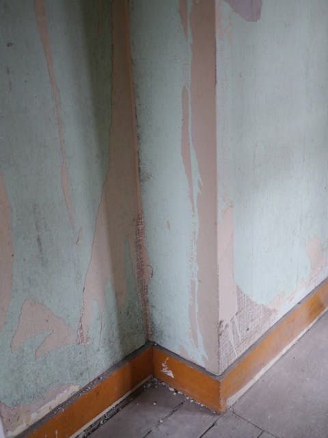 Peeling paint on Safehouse 2 wall highlights venue maintenance for events.