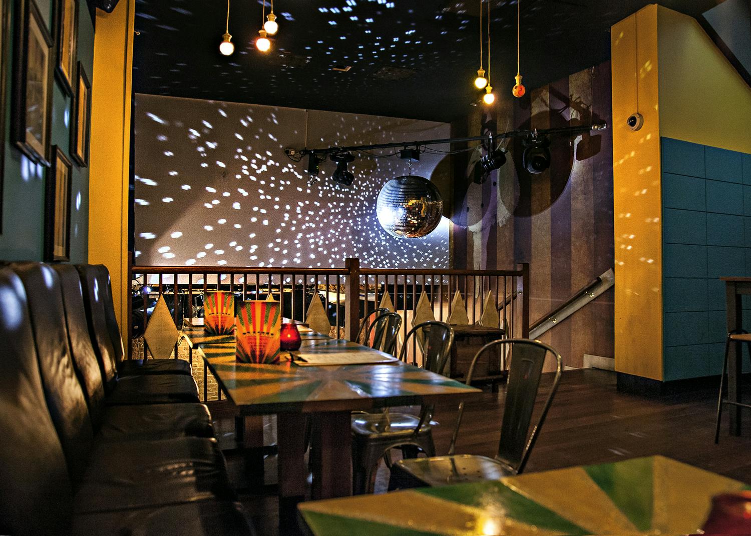 Vibrant event space at Trapeze Bar with colorful decor and disco ball for gatherings.