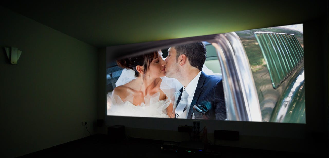 Couple kissing on large screen at Elysion Cinemas, showcasing event visual storytelling.