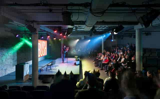 Bush Theatre auditorium with speaker engaging audience at a colorful conference event.