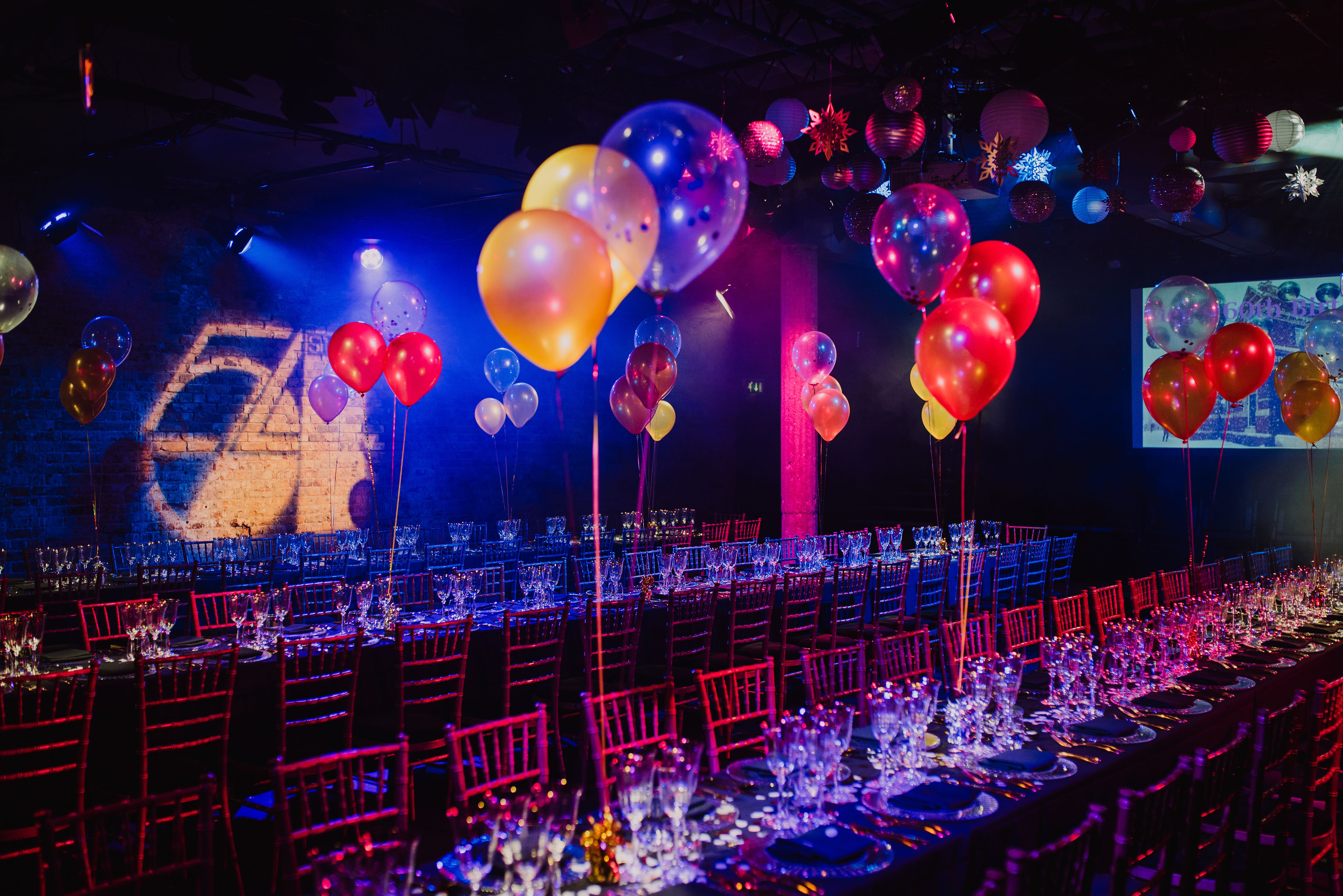 Bush Theatre auditorium set for a vibrant celebration with elegant tables and colorful balloons. - Banner