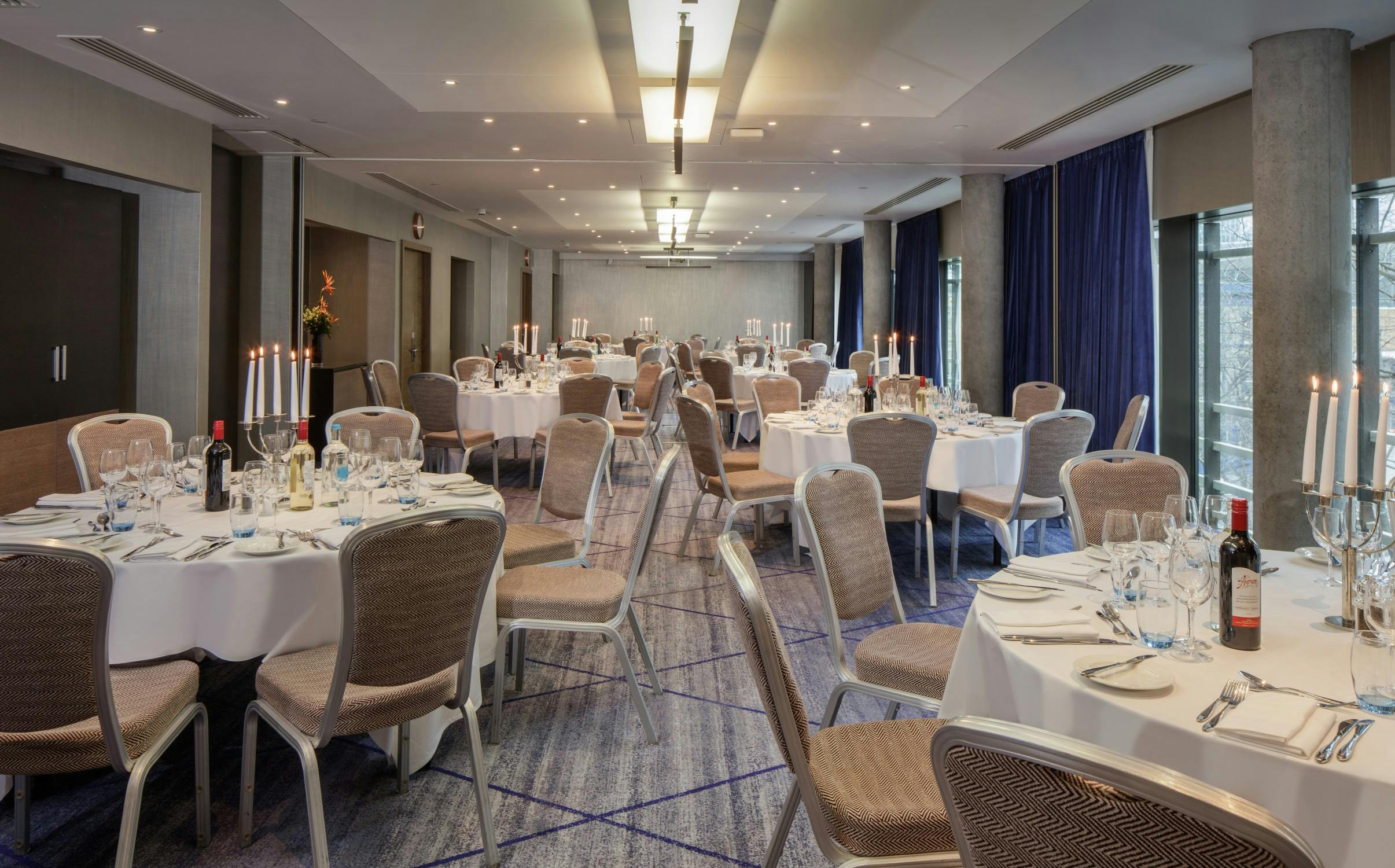 Elegant event space with round tables for corporate dinners at Hilton London Tower Bridge.