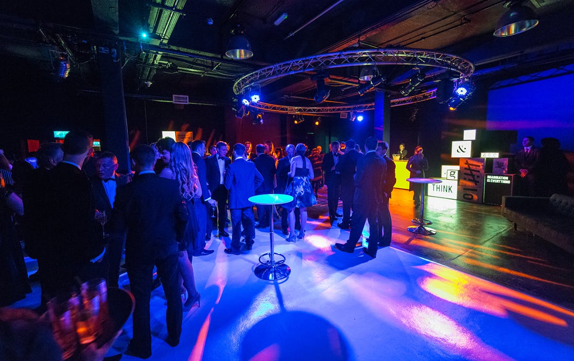 Vibrant networking event in The Black Studio with dynamic lighting and mingling attendees.