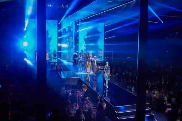 Vibrant fashion show runway with blue lighting at Roundhouse event space.