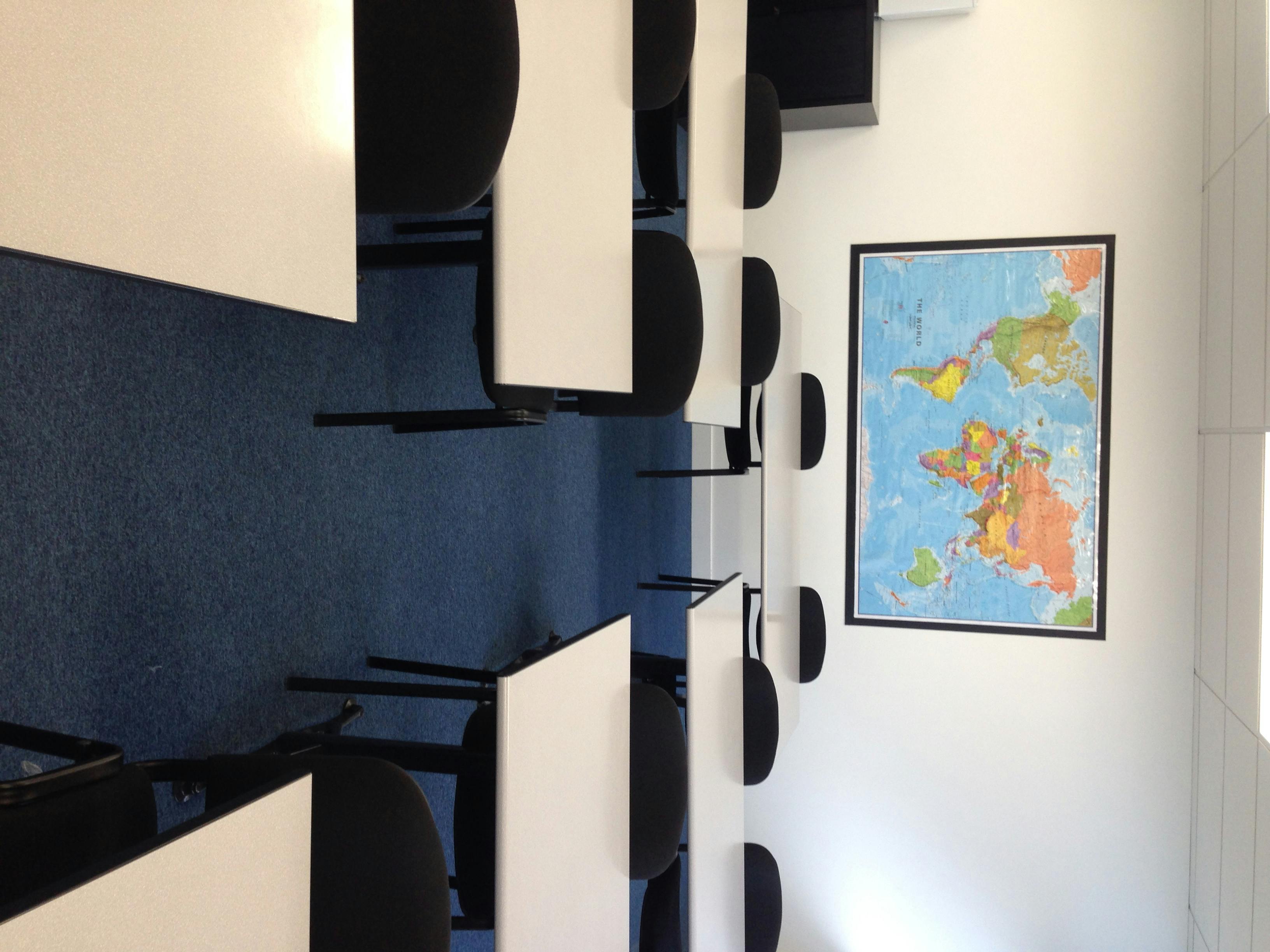 Training room with tables, chairs, and world map for workshops and meetings.