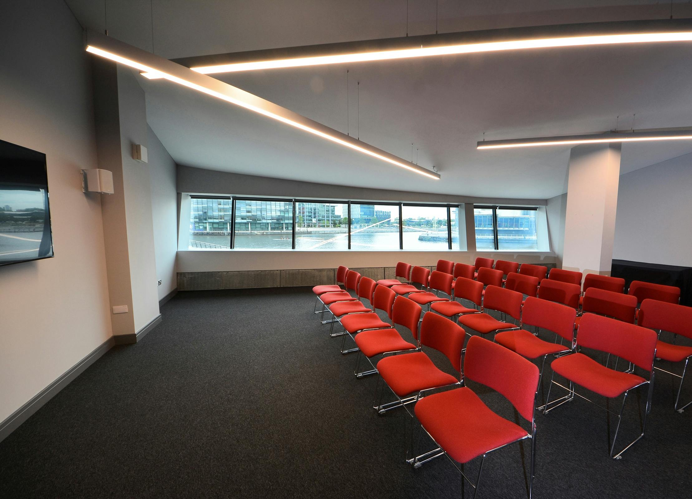 Modern meeting space with red chairs at Imperial War Museum North for events and presentations.