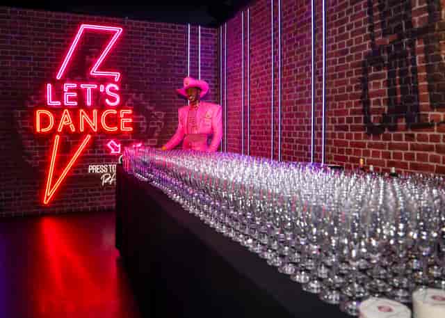Party at Madame Tussauds with neon "LET'S DANCE" sign and elegant glassware.