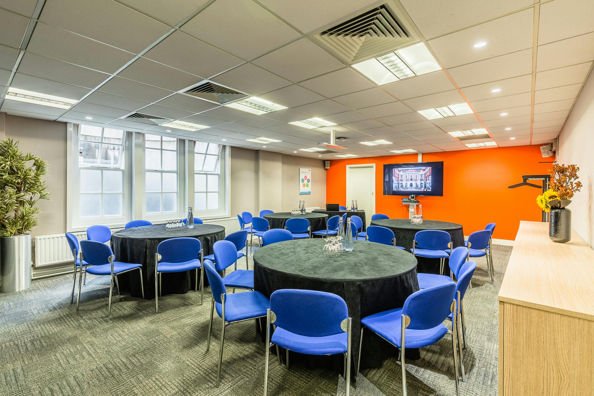 Versatile Dickens Room at BMA House with orange wall, ideal for workshops and meetings.