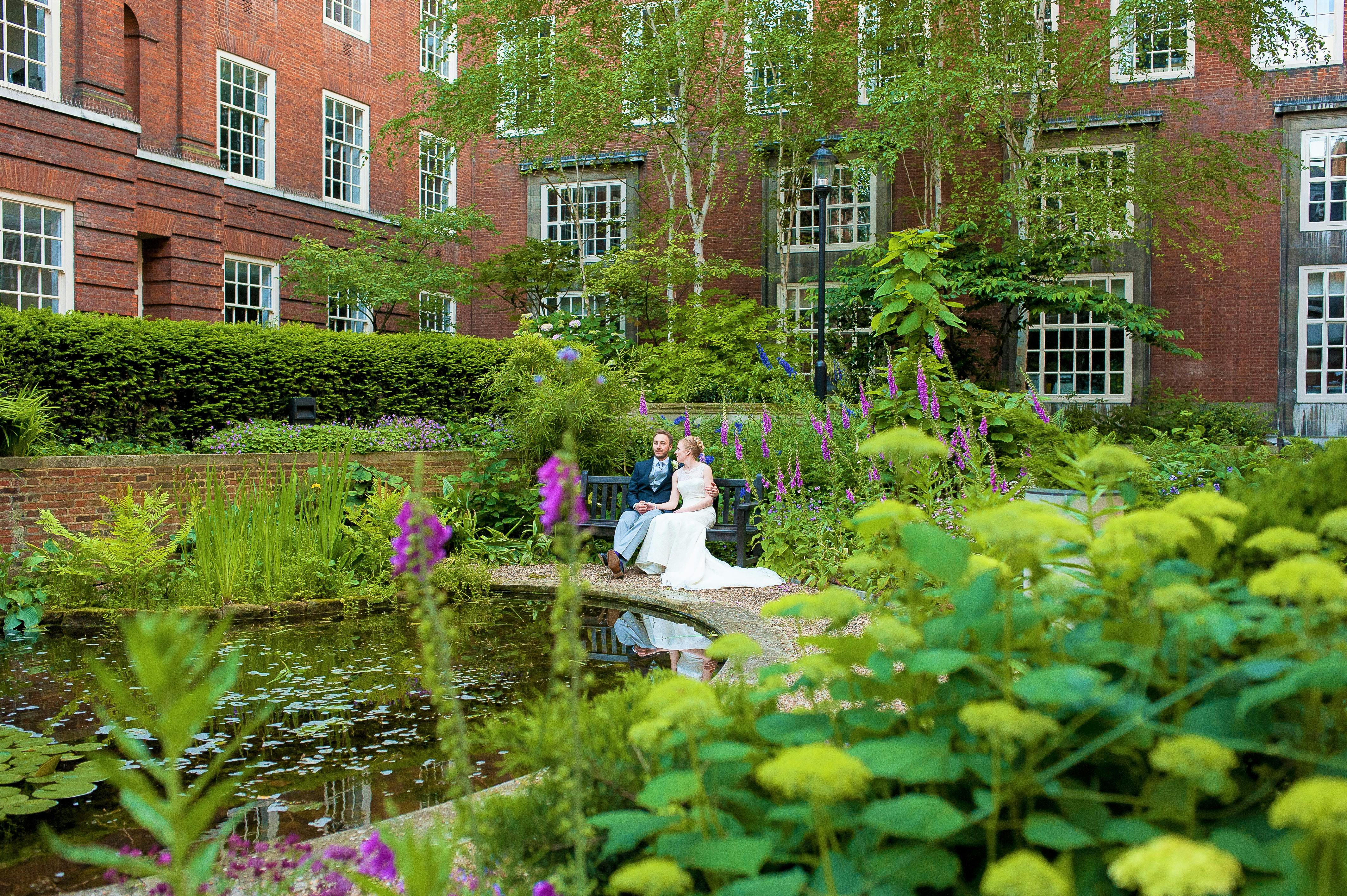 Lush garden venue with vibrant flowers and serene pond, perfect for weddings and events.