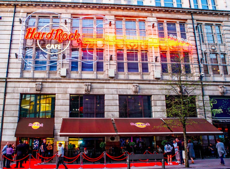 Vibrant Hard Rock Cafe Manchester exterior with neon signage for events and gatherings.