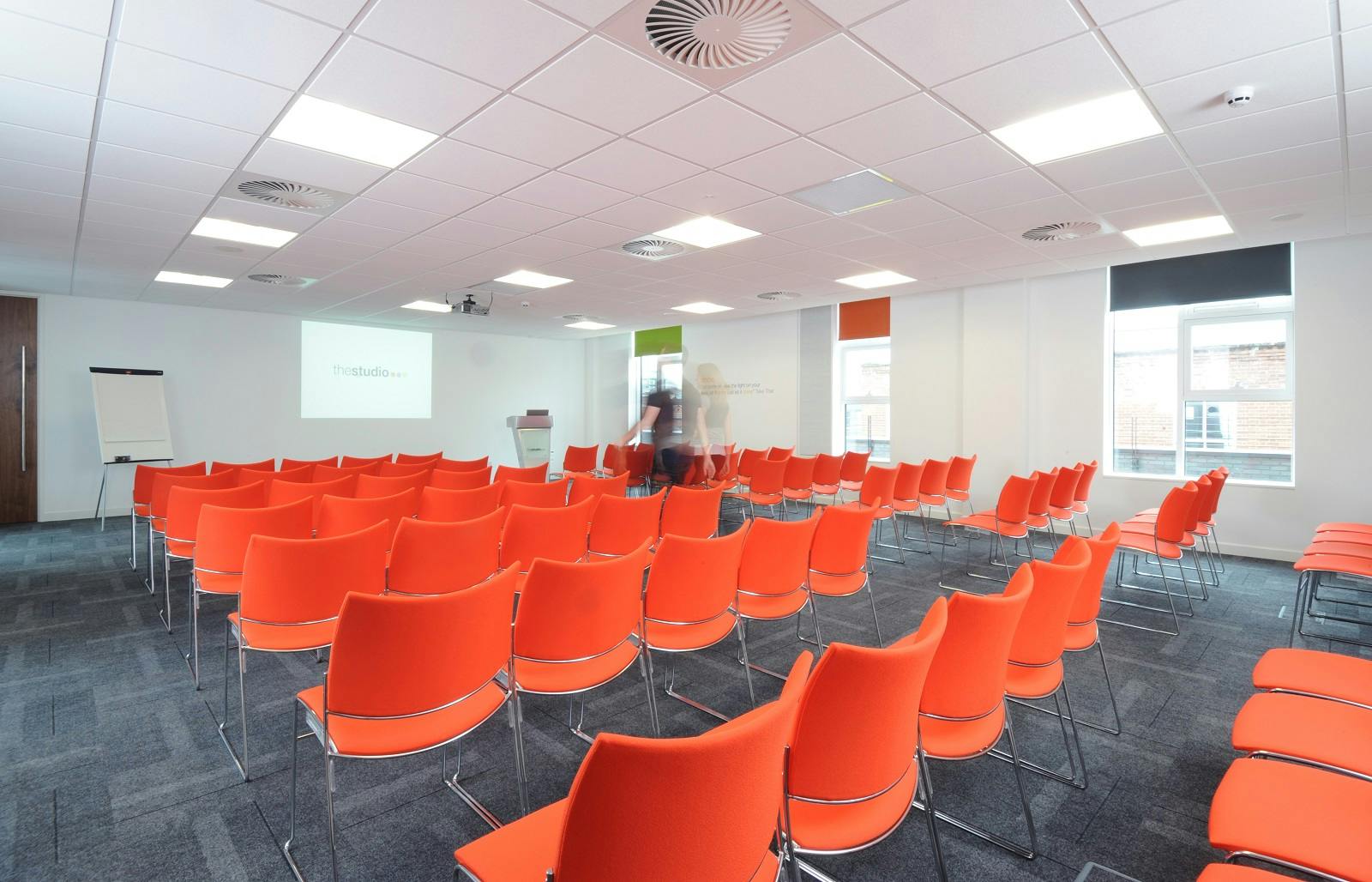 Modern meeting space with orange chairs, perfect for workshops and presentations.