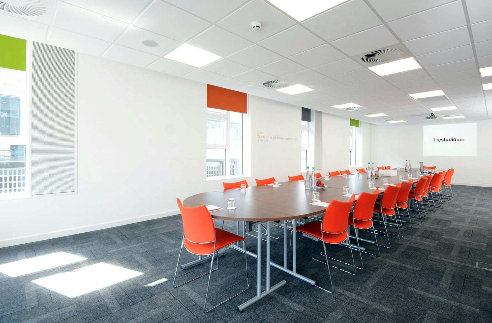 Modern meeting room at Grow in thestudio Manchester with oval table and orange chairs.