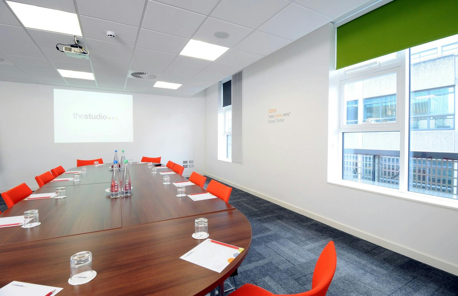 Modern meeting room in Manchester with oval table and orange chairs for collaboration.