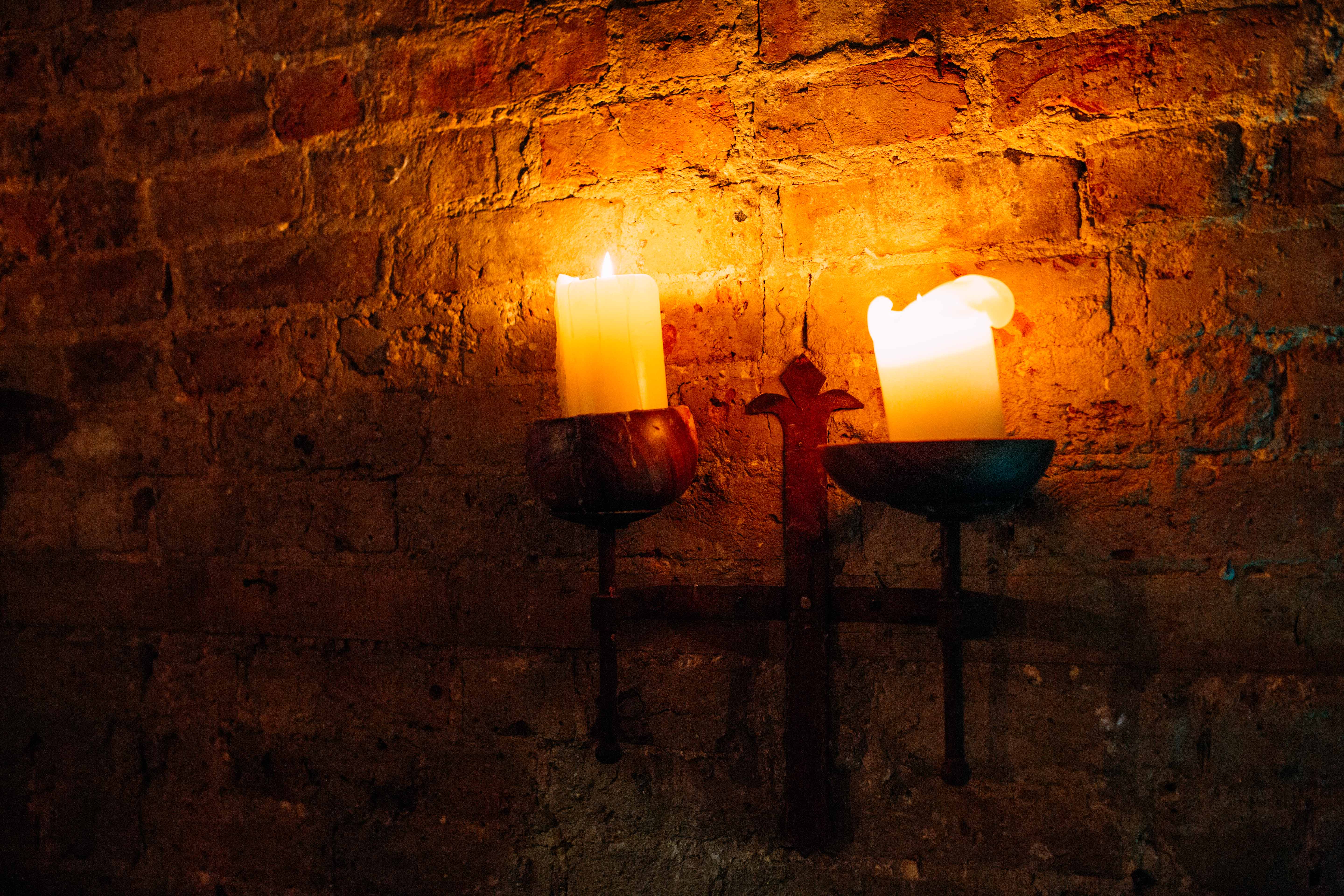 Cozy candlelit venue with rustic brick wall for intimate gatherings and events. - Banner