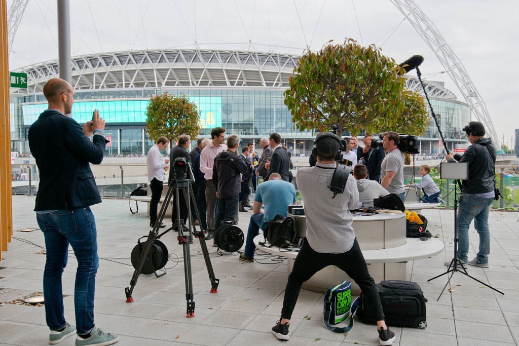 Outdoor event setup at Wembley Stadium with professionals networking and media coverage.