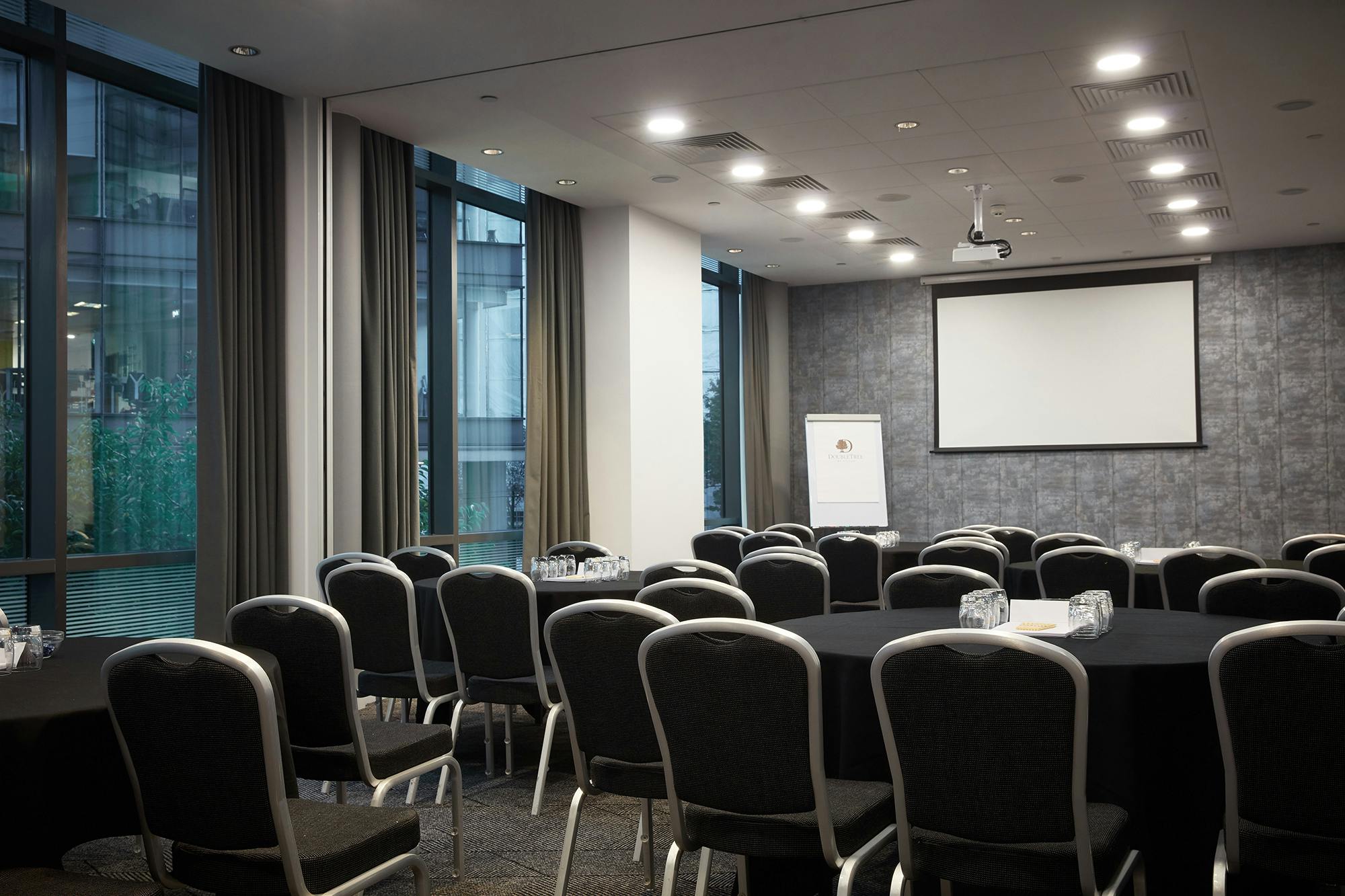 Meeting room at DoubleTree Manchester with round tables, ideal for workshops and presentations.