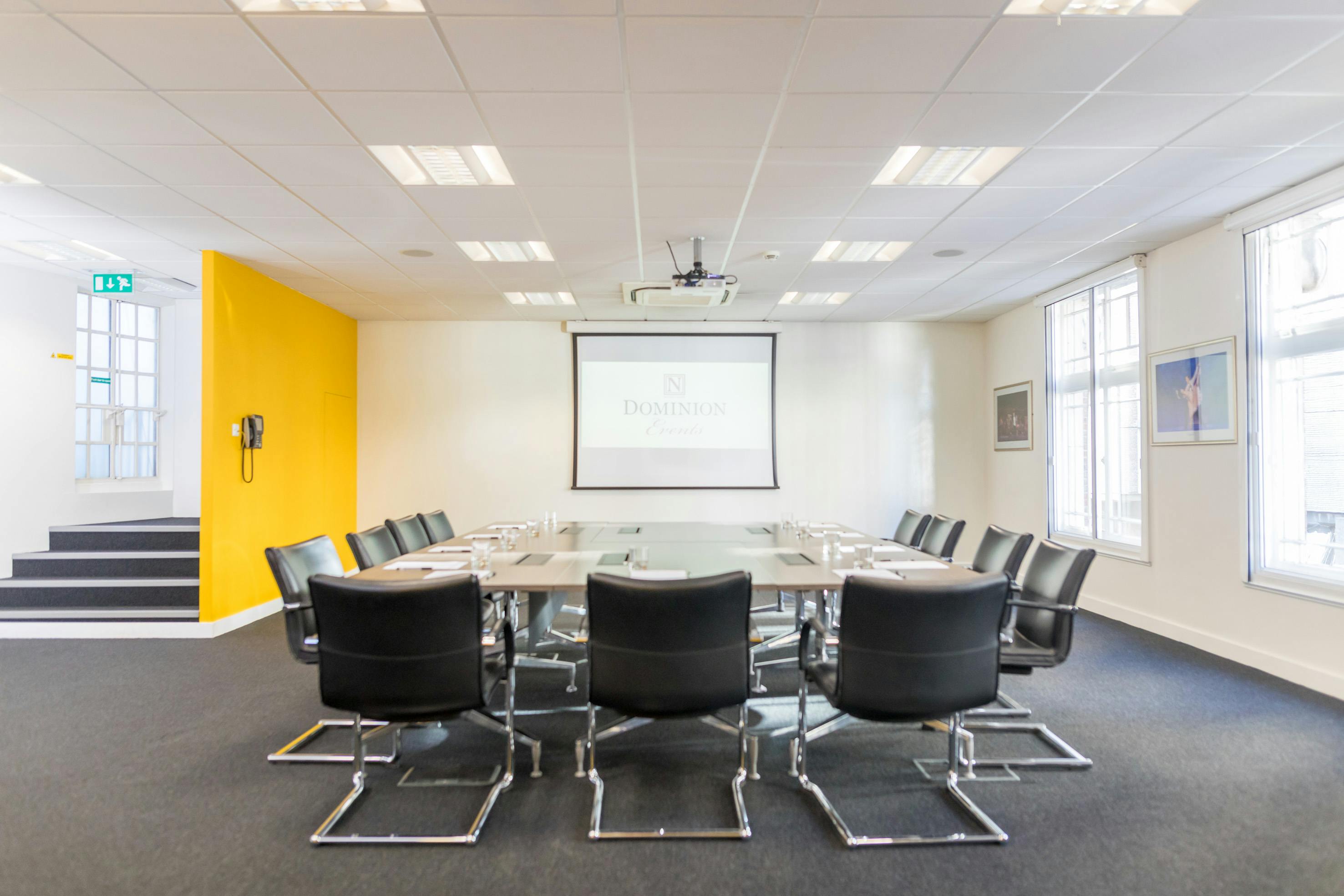 Modern conference room at Dominion Theatre with glass table, ideal for meetings and presentations.