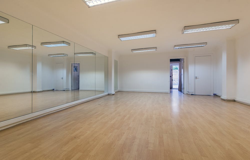 Versatile event space with hardwood floors and mirrors, perfect for workshops and fitness classes.