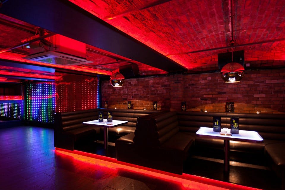 Stylish event space with black booths and red lighting, perfect for networking or parties.