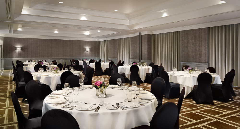Elegant Symphony Ballroom setup for formal events with white tablecloths and floral centerpieces.