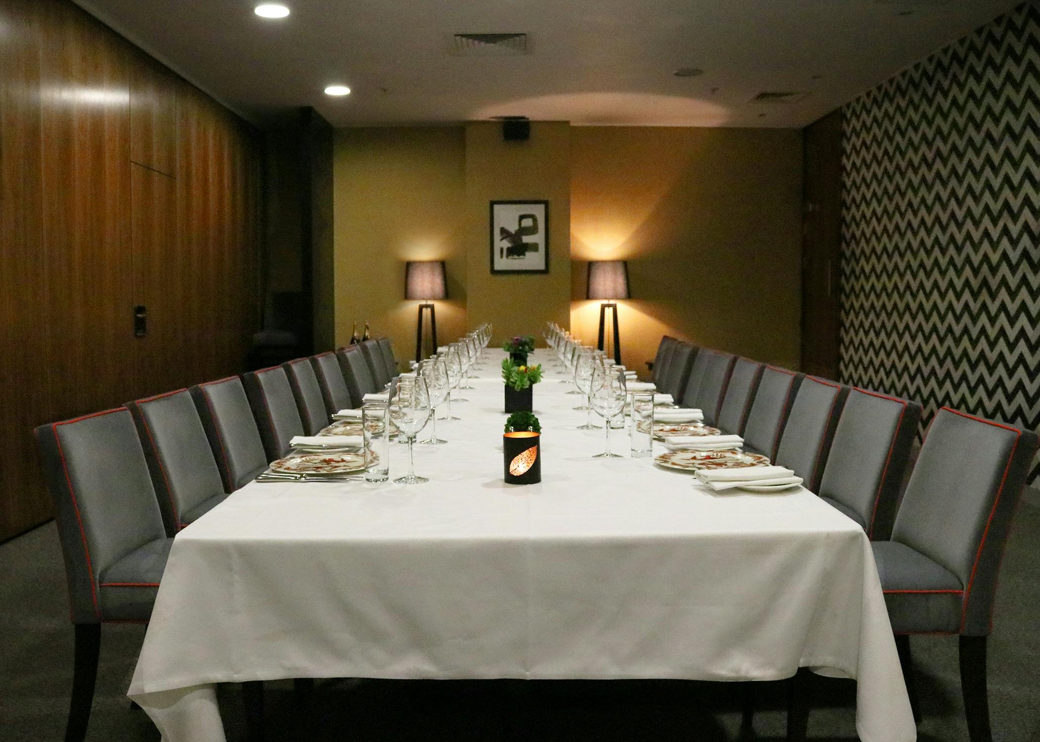 Elegant meeting room with long table set for formal dinner at Opus Restaurant.