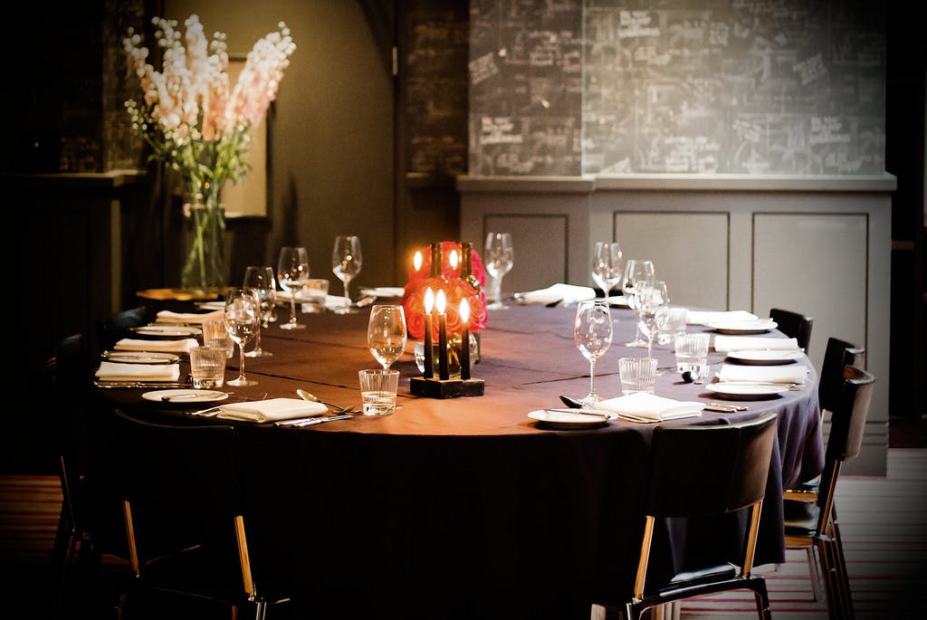 Elegant round dining table with candles in Malmaison London for intimate dinners or events.