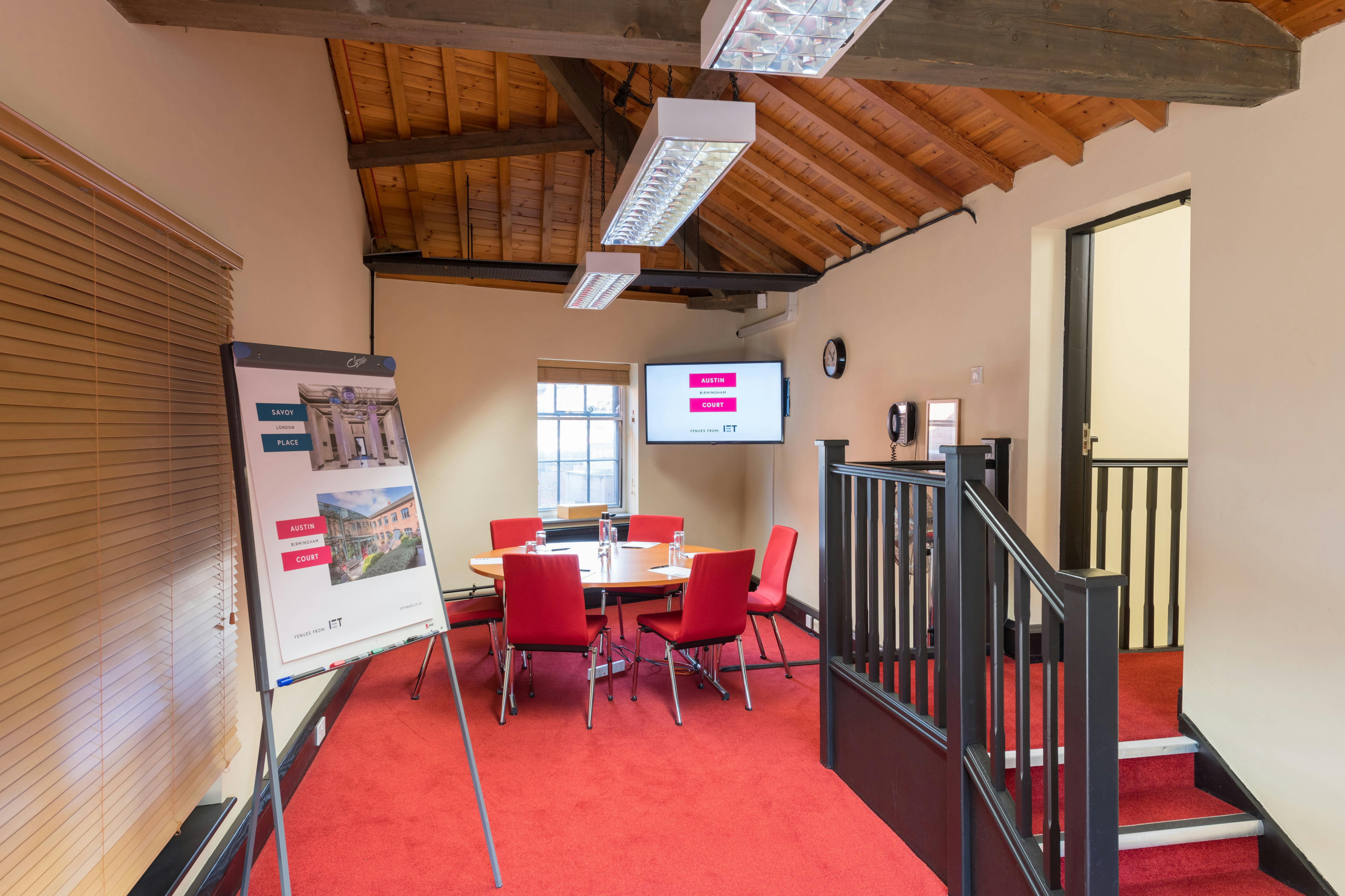 Stephenson Room at IET Birmingham: round table, vibrant red chairs, meeting space.