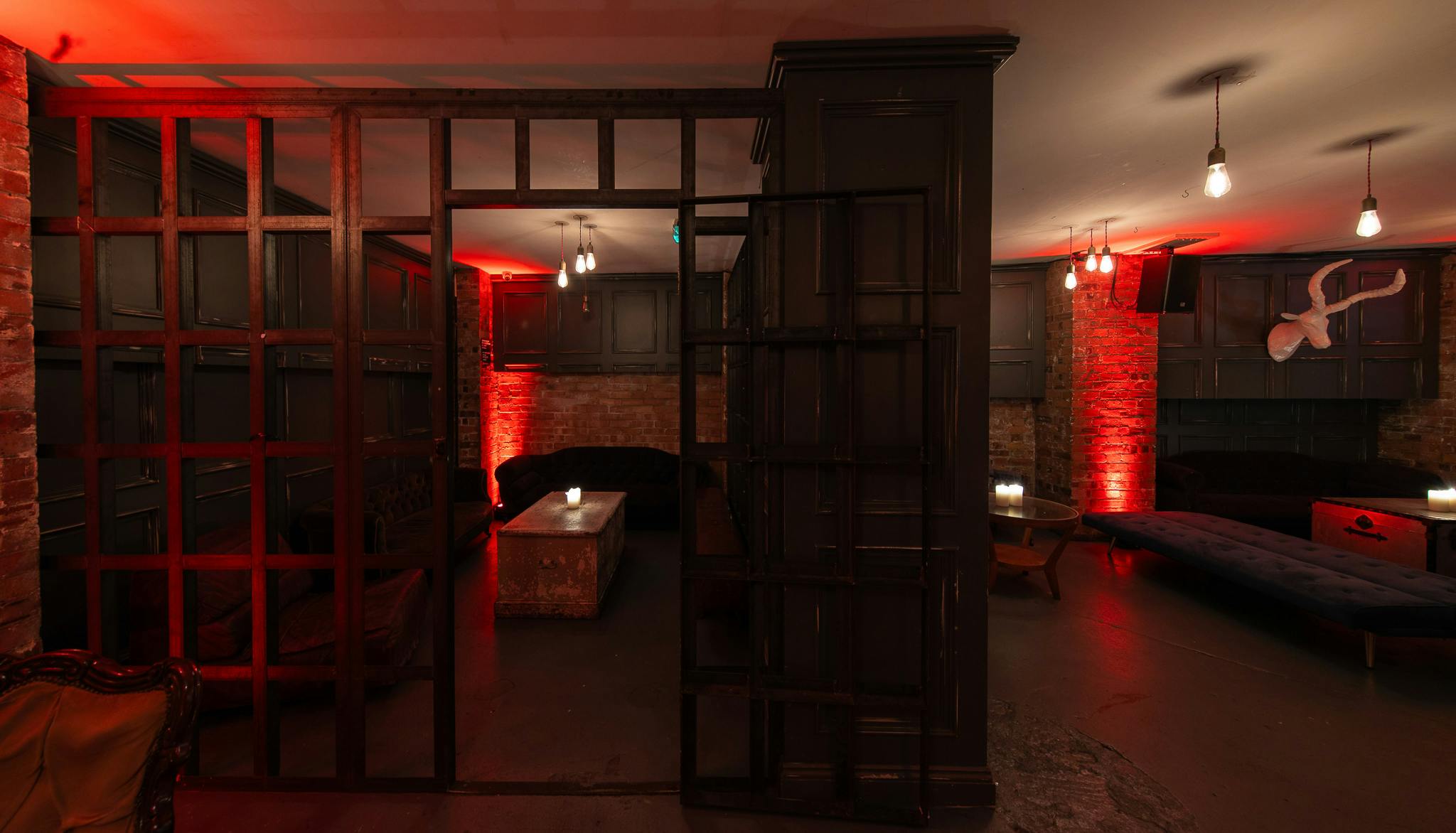 Intimate event space at The Secret Bar with warm red lighting for networking and gatherings.