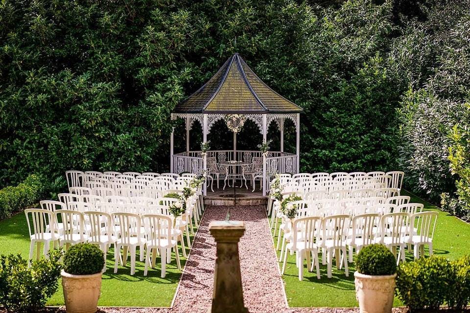 English Garden Bandstand gazebo with white chairs, ideal for outdoor weddings and events.