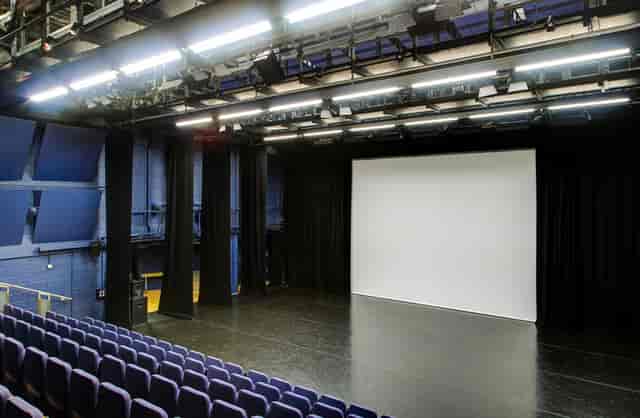 Lilian Baylis Studio stage with projection screen, perfect for workshops and performances.